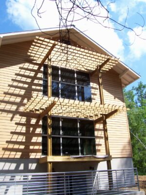 Two story beige house with wooden sunshades.