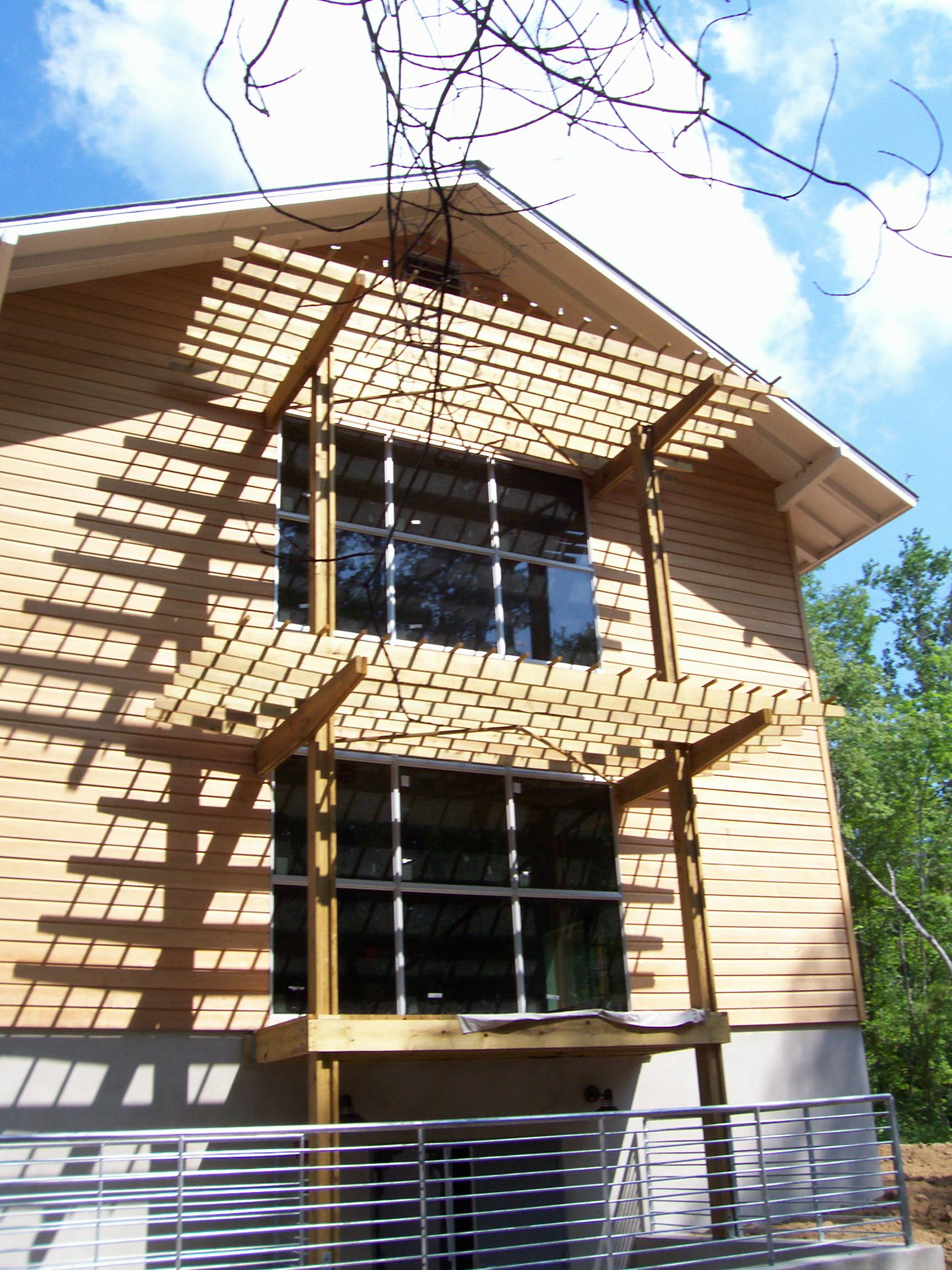Two story beige house with wooden sunshades