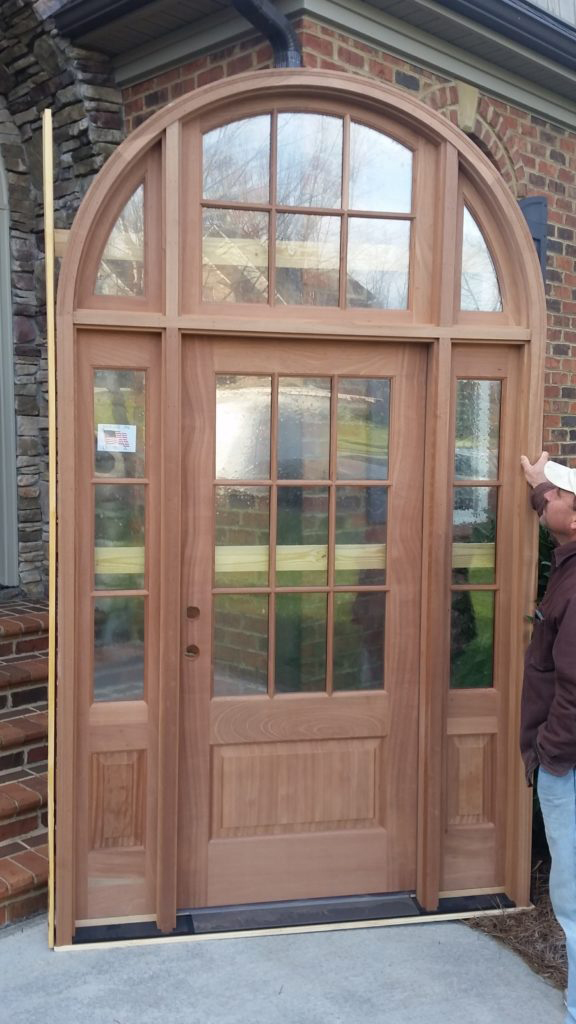 Arched wooden front door with sidelights