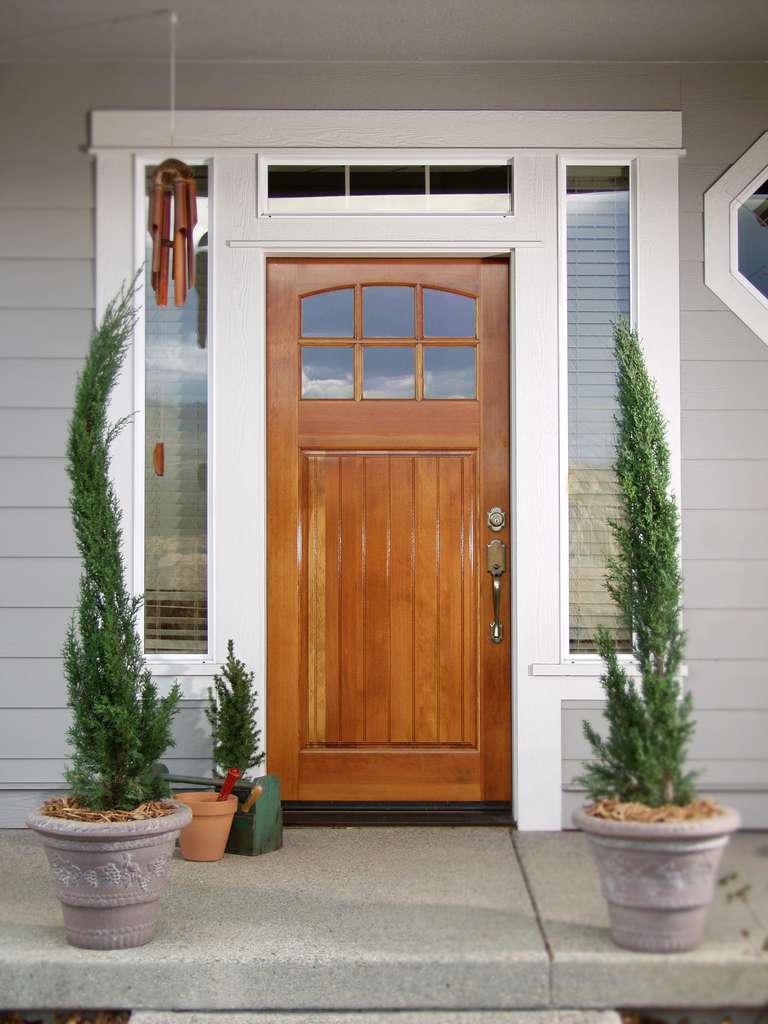 Wooden front door with potted evergreen plants