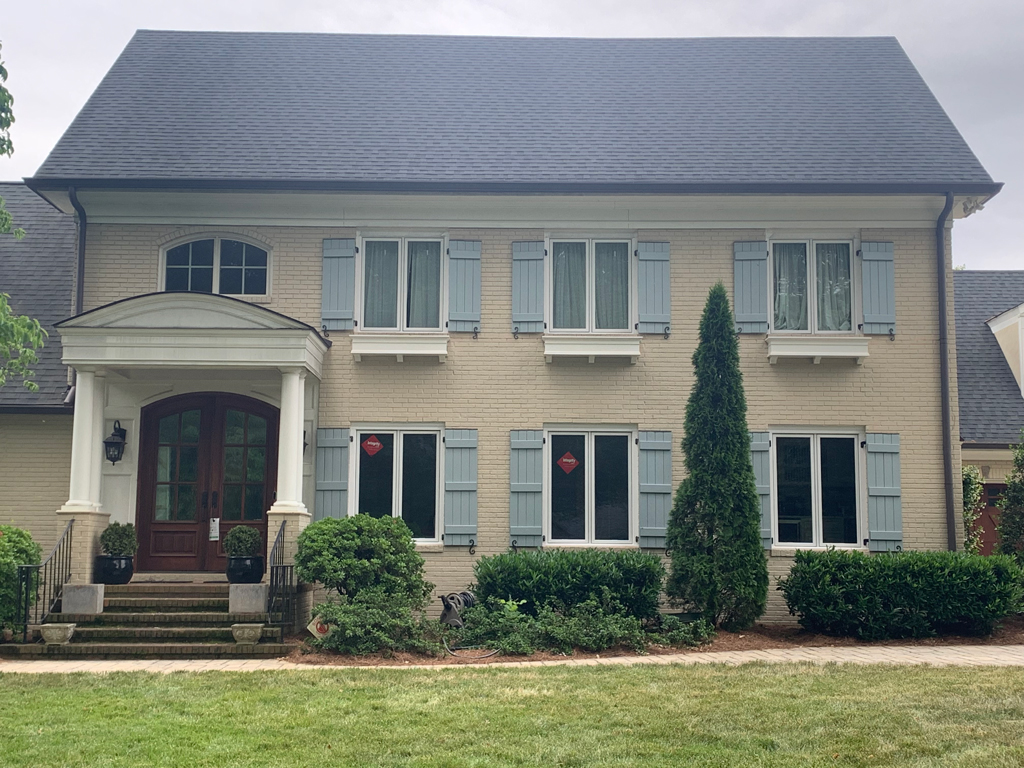 Two-story beige brick house with blue shutters