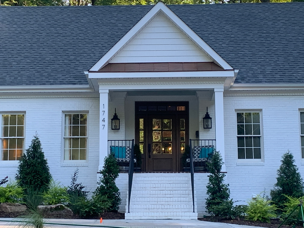 White brick house with gabled porch and steps