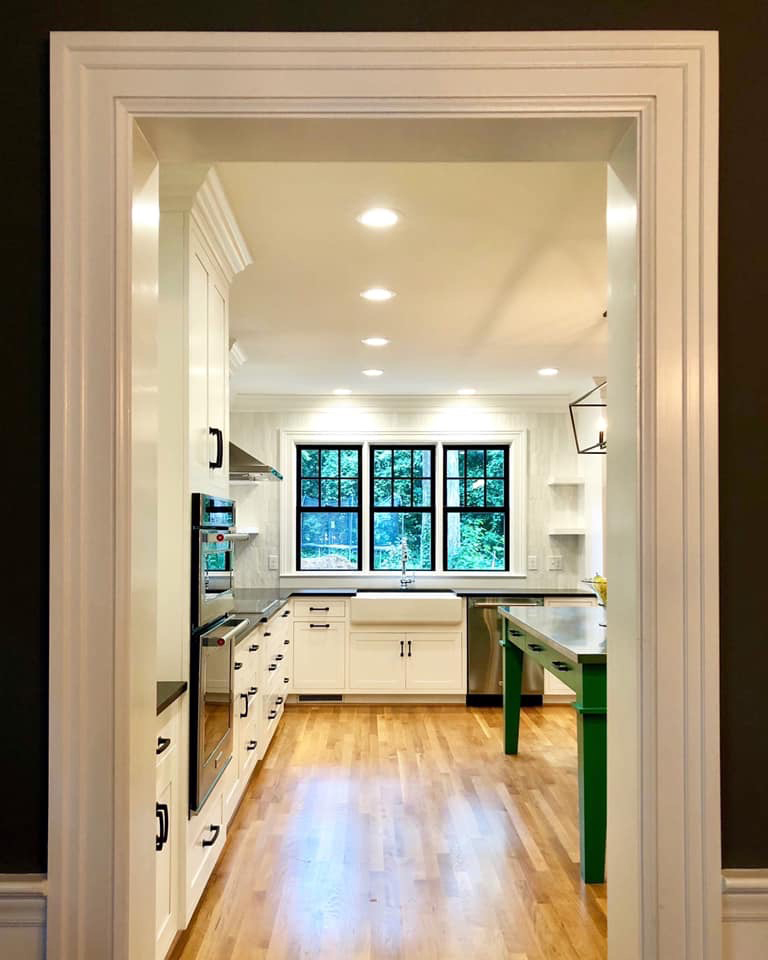 Bright white kitchen with green island and windows