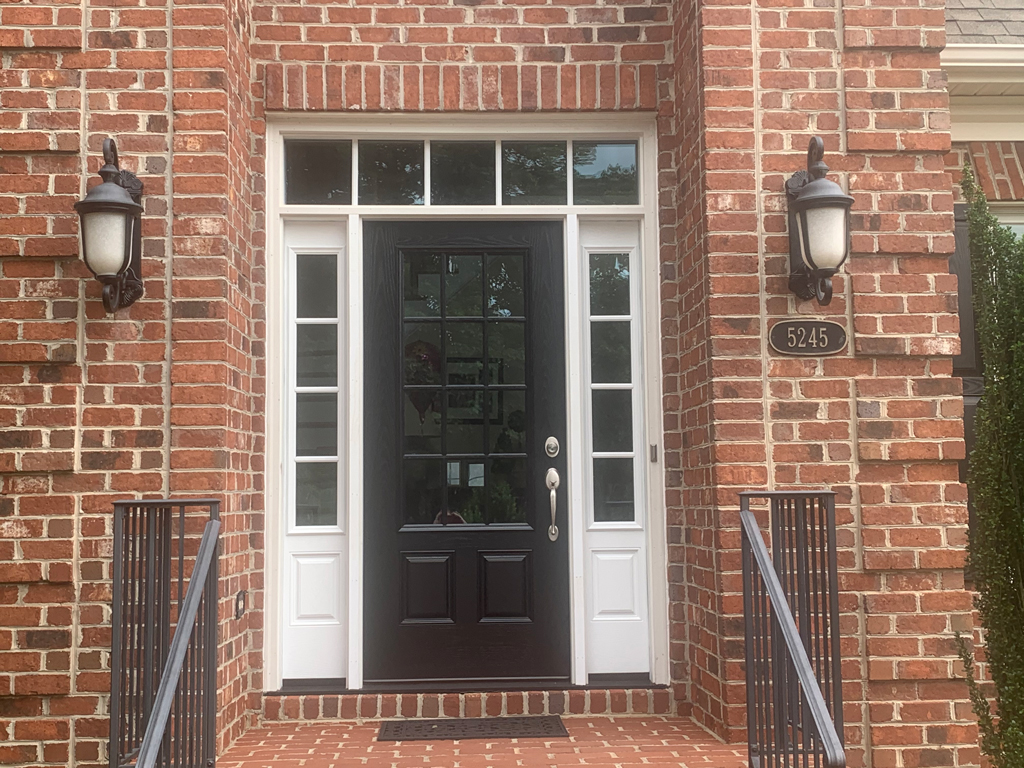 Brick house entrance with black door and lanterns