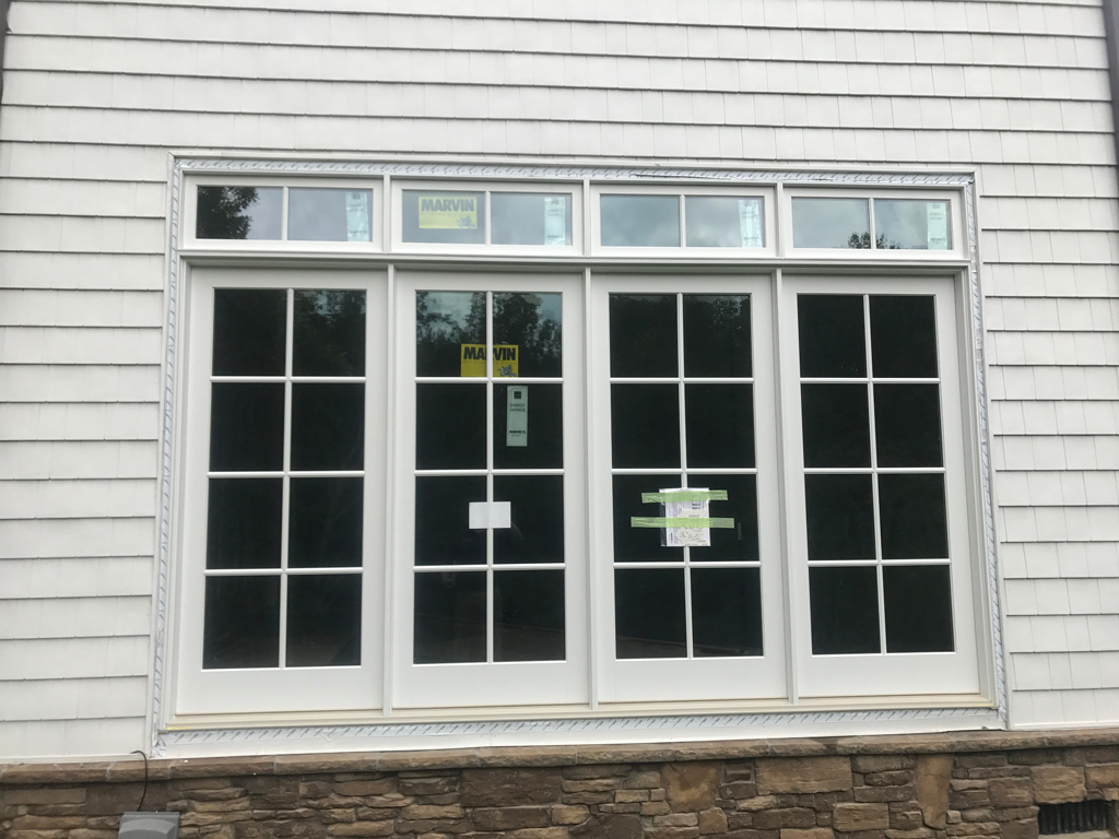 Large four-panel white window over stone base