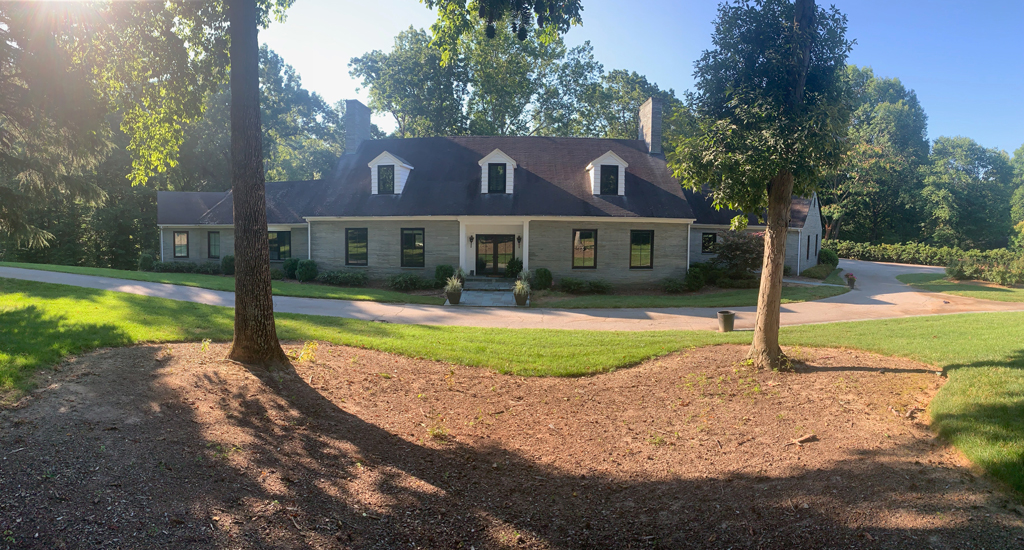 Ranch-style house with driveway and trees