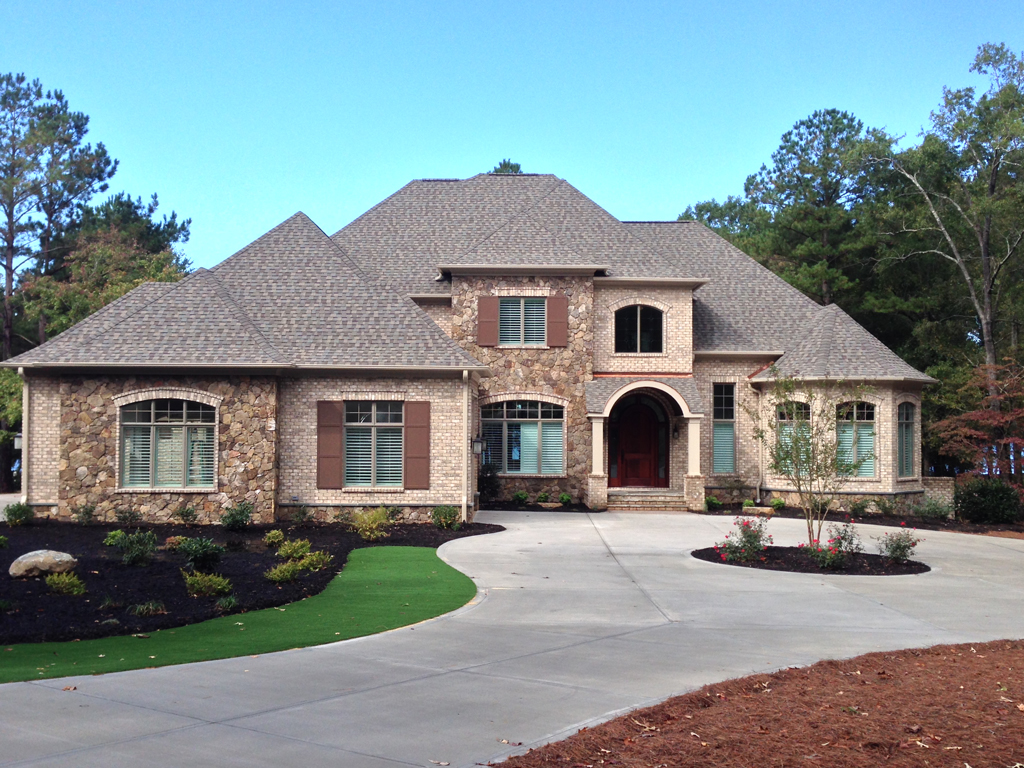 Stone suburban house with driveway and landscaping