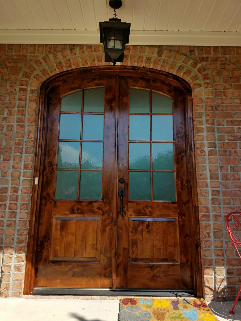 Arched wooden double front doors with glass panes