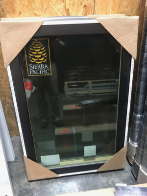 Packaged black-framed casement window with sticker.