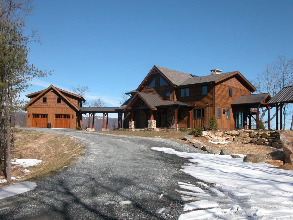 Large wooden mountain lodge with snowy driveway