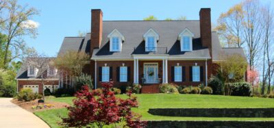 Brick colonial home with dormers and manicured lawn.