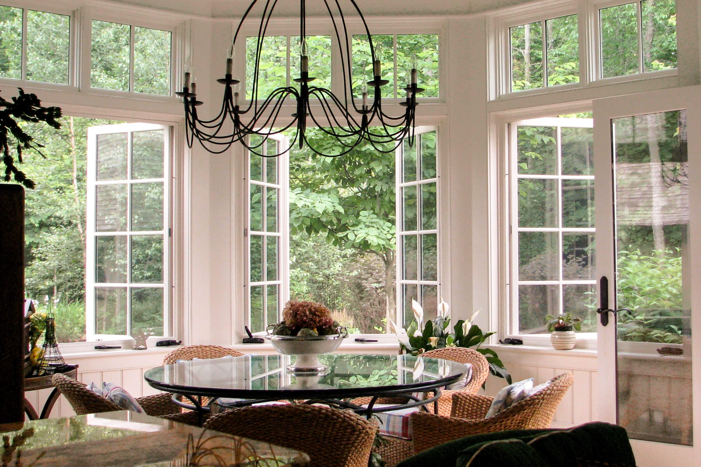 Sunlit dining nook with chandelier and greenery